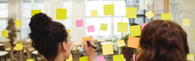 Business executives writing on sticky notes