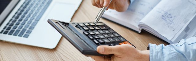 Plano medio de unas manos sujetando una calculadora representando el calculo del CAC Payback Period.